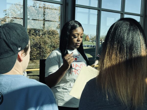 Woman standing in front of window speaking to students.