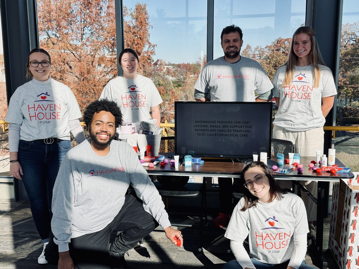 Six students smiling by donation table.