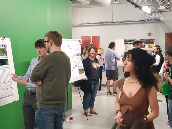Students walking through the MEEC with various poster boards and presenters